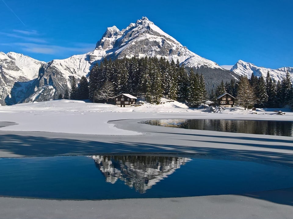 Ein halb zugefrorener See und Berge im Hintergrund.