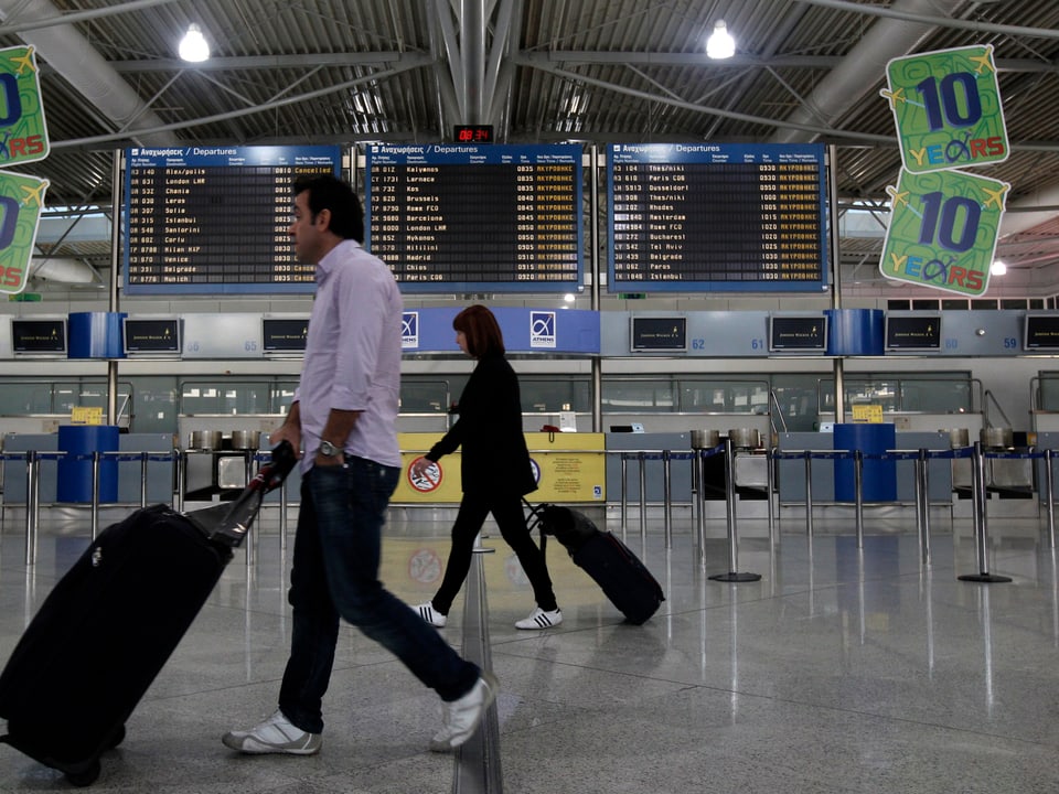Zwei Passagiere laufen durch die Wartehalle eines Flughafens