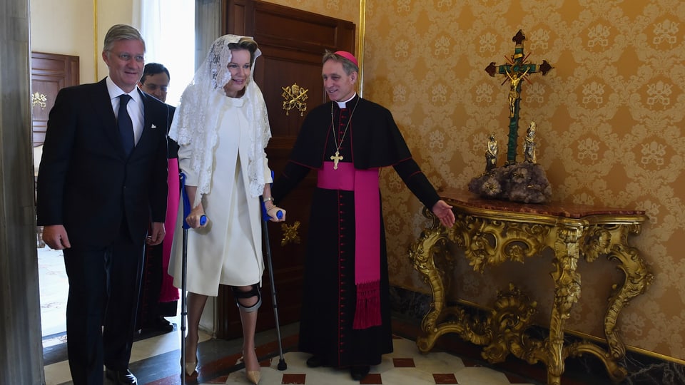 König Philippe und Königin Mathilde laufen durch Tür.