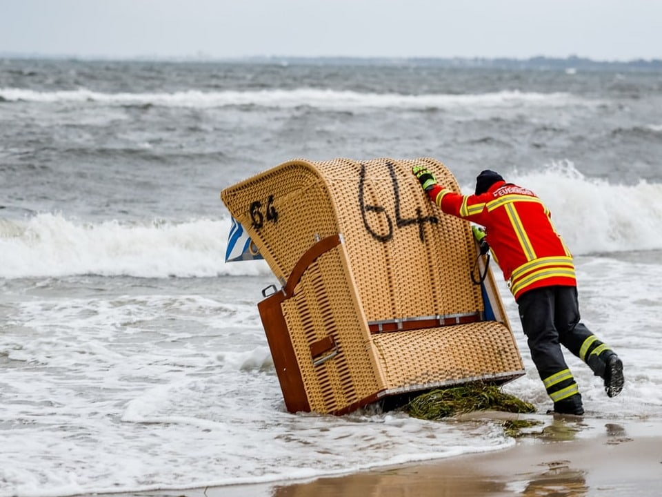 Feuerwehrmann versucht einen Sitzkorb aus dem Meer zu holen.