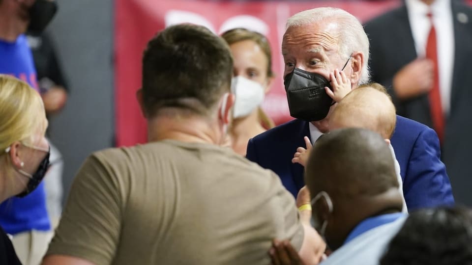 Joe Biden mit Maske und Baby auf dem Arm