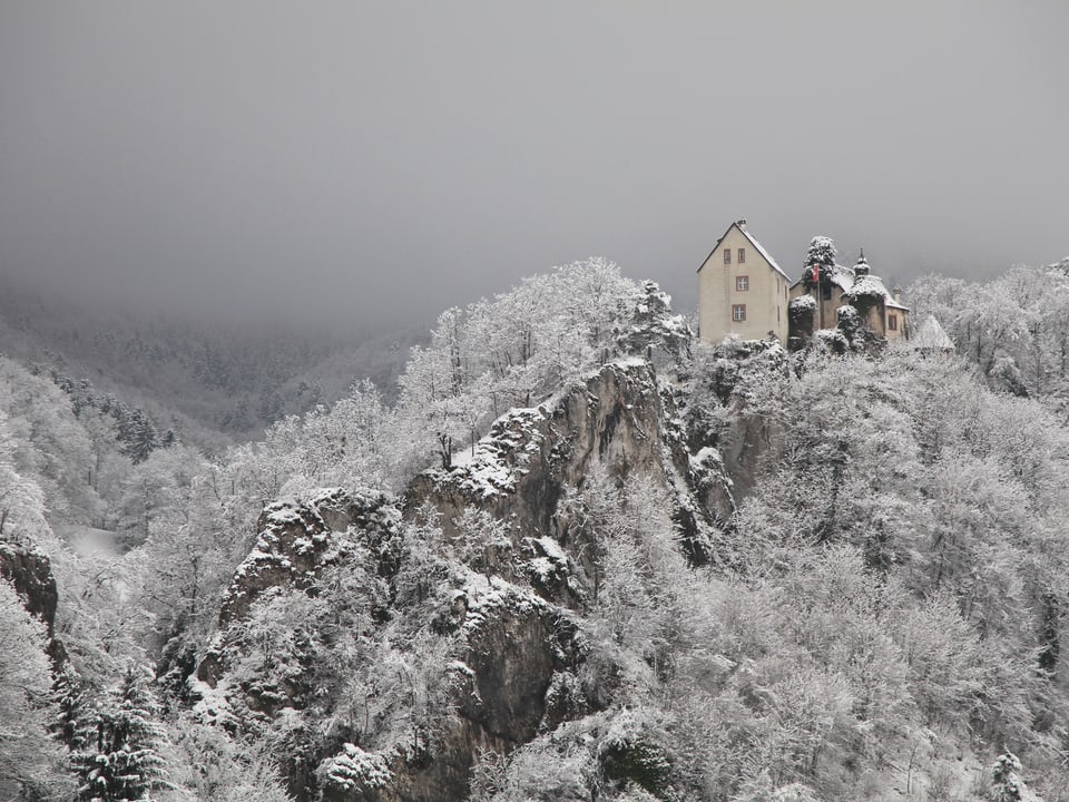 Ein Schloss auf einem Felsen im Schnee.