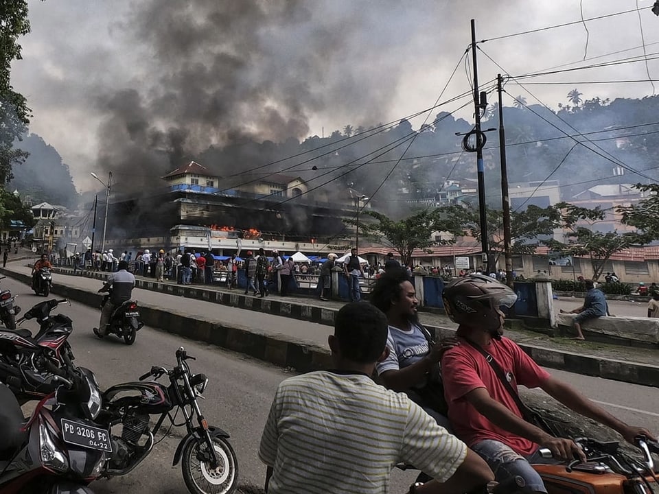 Demonstranten in West Papua und ein brennendes Haus