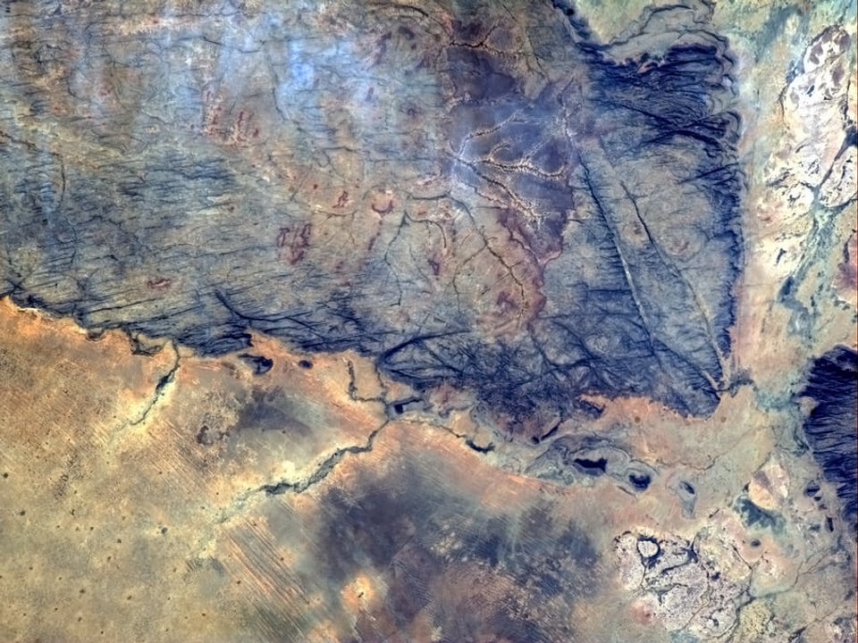 Blick aus dem Orbit auf die Südsahara. Die Farben variieren von Okker bis Violett.
