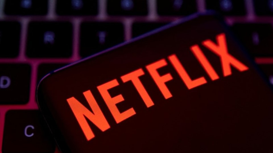 Schrift Netflix in Rot auf dunklem Hintergrund, Handy, Tastatur.