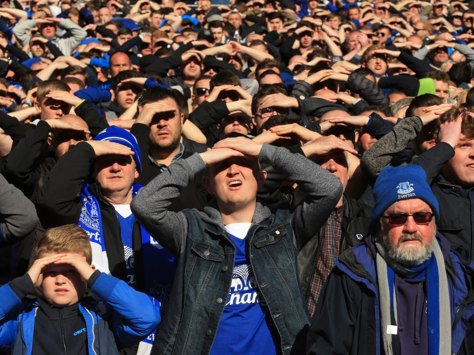 Fans von Everton schützen die Augen vor der Sonne.