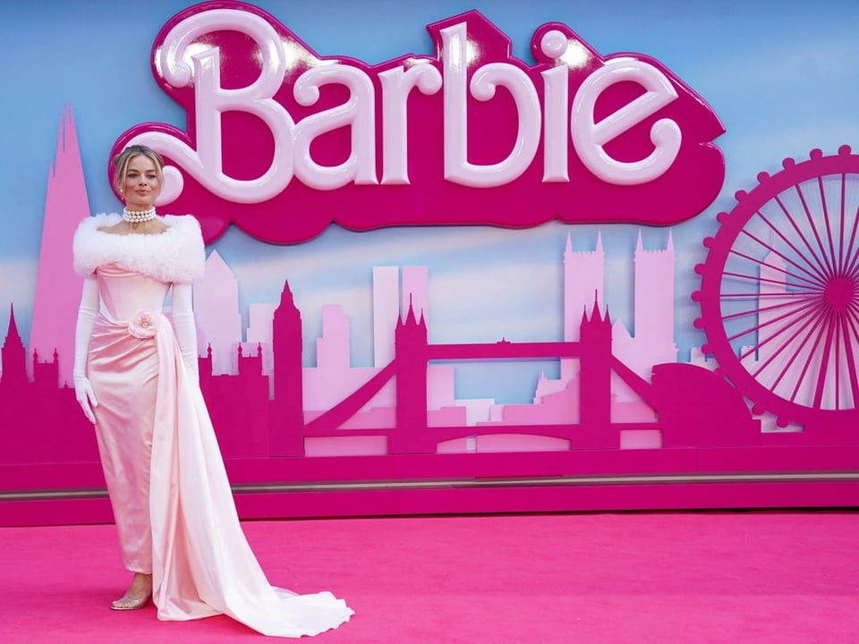 Margot Robbie vor einem Barbie-Plakat.