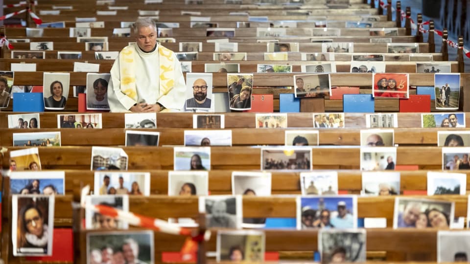 Pfarrer sitzt in leeren Bänken mit Fotos von Gläubigen bestückt
