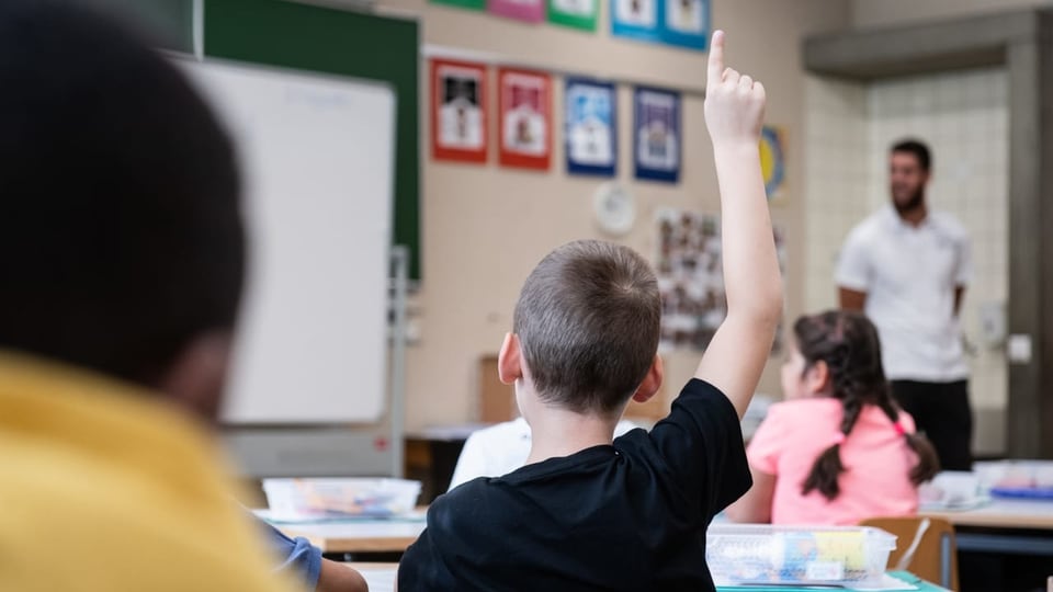 Ein Schüler streckt seine Hand auf im Schulunterricht