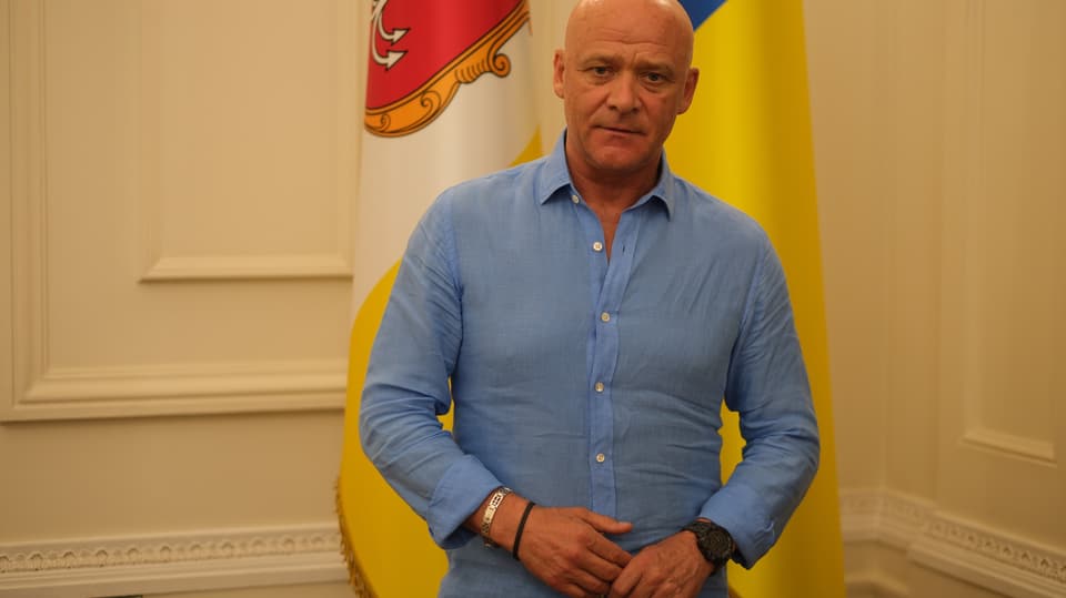 Truchanow im Porträt vor der Flagge der Stadt stehend.
