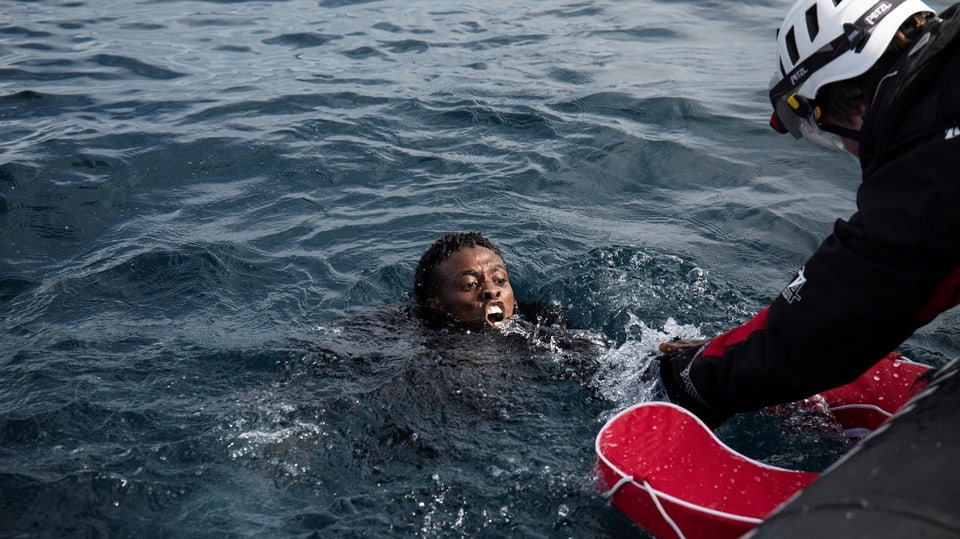 Ein Mensch wird von einem Helfer aus dem Meer gezogen