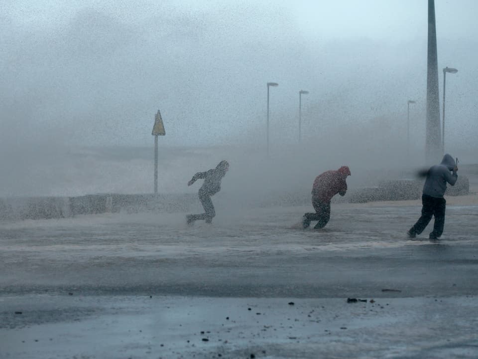 5.12.2013 In Rhyl im Norden von Wales fliehen Passanten vor der Gischt. 