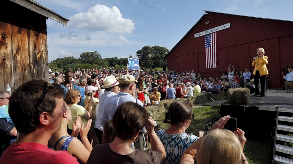 Hillary Clinton steht auf einer Bühne neben einer Farm 