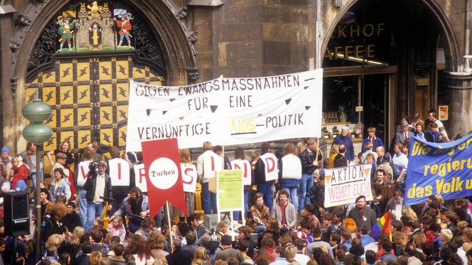 eine Menschenmenge vor altem, grauen Gebäude. Ein Plakat: «Gegen Zwangsmassnahmen. Für eine vernünftige Aids-Politik».