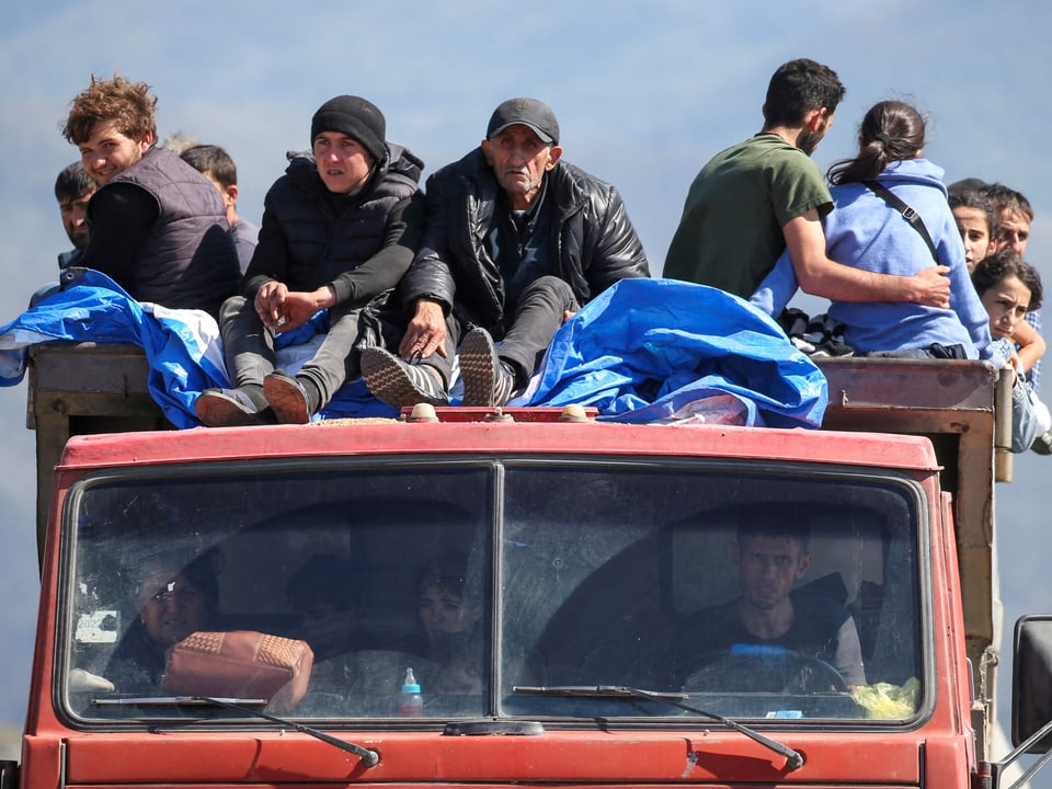 Armenierinnen und Armenier fahren mit einem Bus und sitzen auch auf dem Dach.