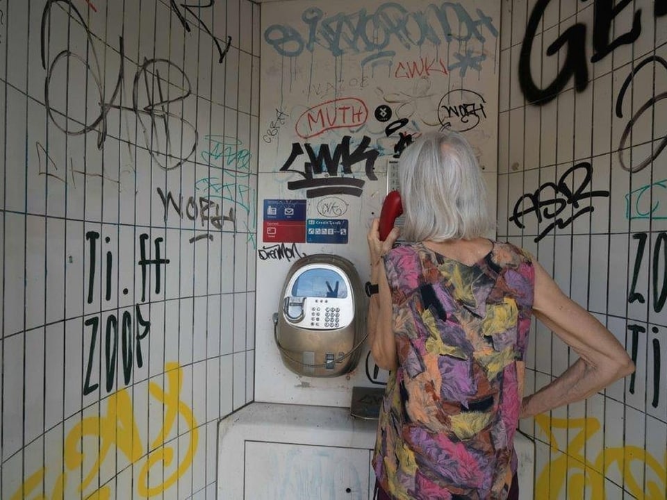 Eine Frau telefoniert in einer Telefonkabine.