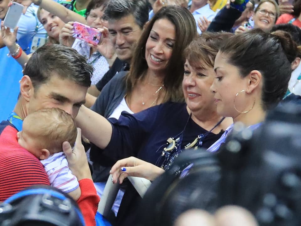 Michael Phelps hält ein Baby im Arm.