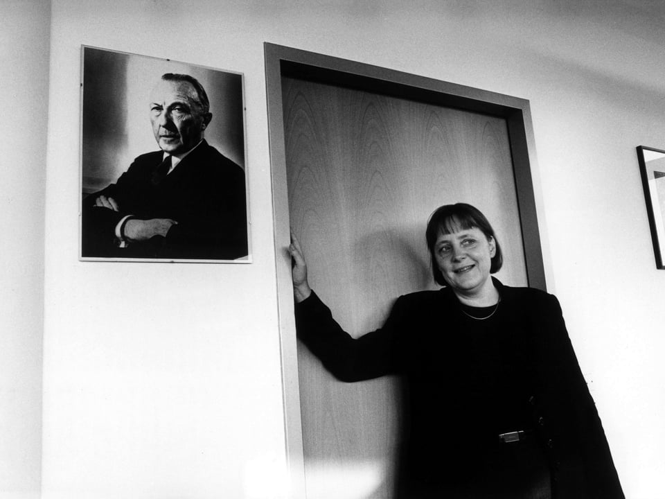 Angela Merkel steht neben einem Foto von Konrad Adenauer.
