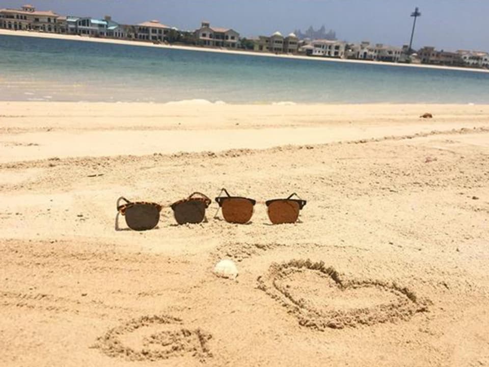 zwei Sonnenbrillen ein "G" und ein Herz am Strand