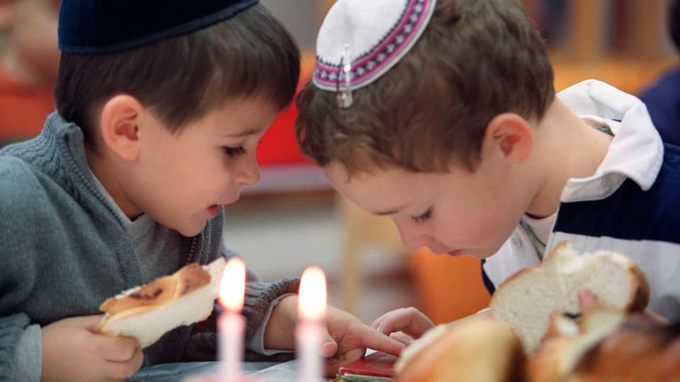 Zwei jüdische Kinder schauen gemeinsam etwas an.