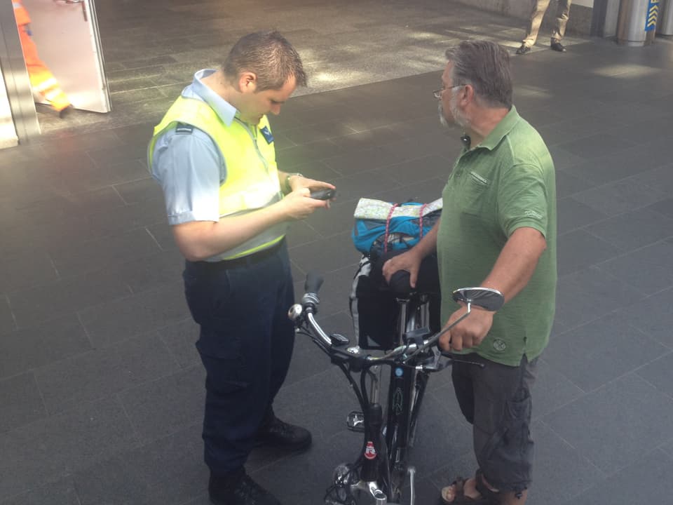 Securitrans-Mitarbeiter gibt einem Velofahrer mit Bart eine Fahrplan-Auskunft. 