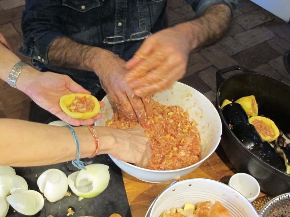 Zwei Paar Hände füllen Gemüse mit Reis in Tomatensauce
