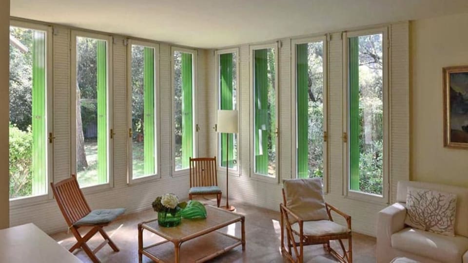 ein Wohnzimmer mit Holzstühlen und grossen Fenstern