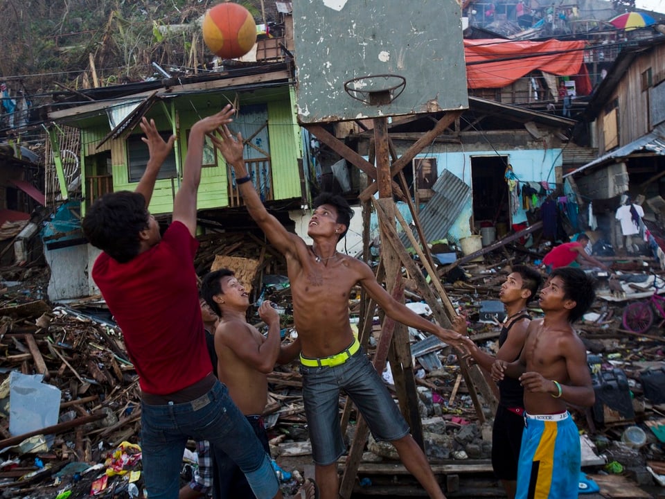 Junge Männer spielen zwischen den Trümmern von Tacloban Basketball.