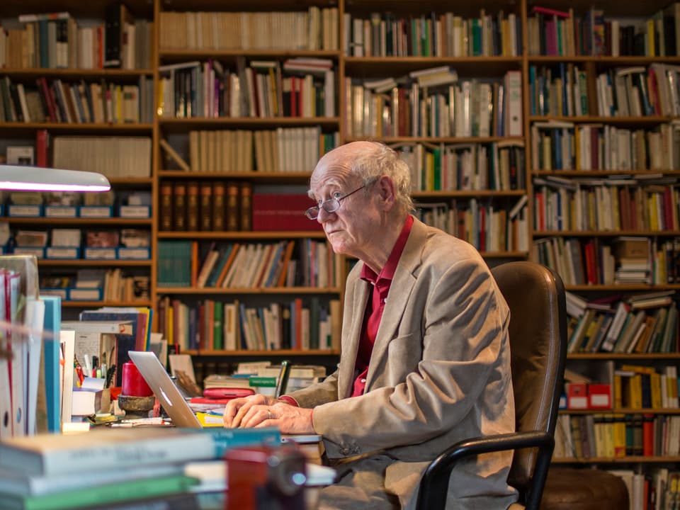 Der Schweizer Schrifsteller Franz Hohler sitzt in seinem Arbeitszimmer am Schreibtisch.