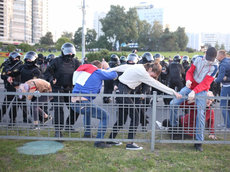 Protestierende setzen sich gegen uniformierte Polizisten mit Schlagstöcken zur Wehr.