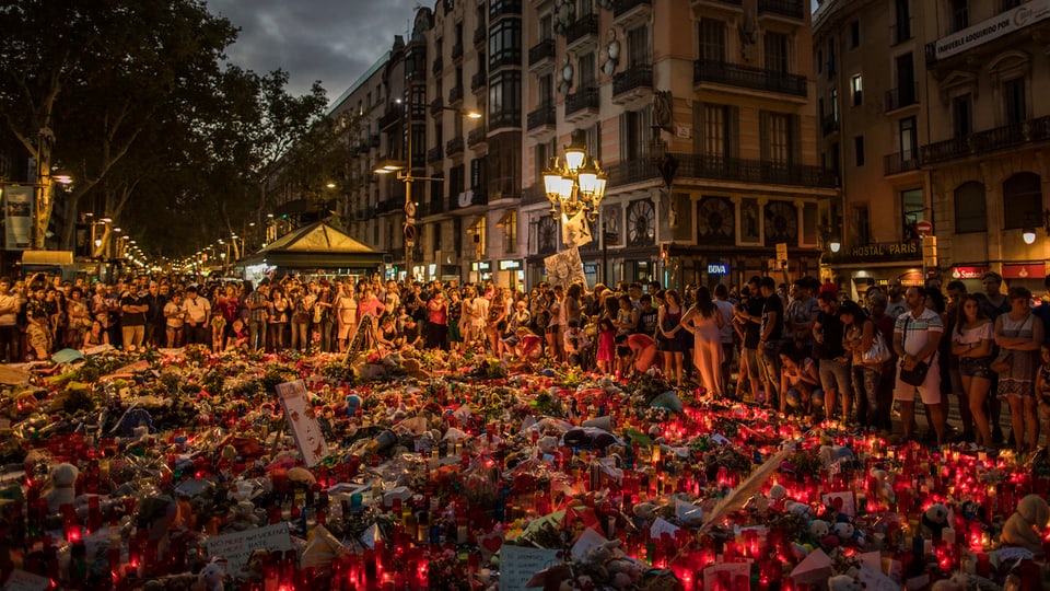 Meer von Blumen und Kerzen am Ort des Anschlags mit vielen Menschen im Hintergrund