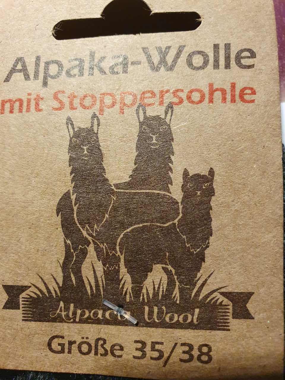 Foto des Etiketts der Socken. Es besagt «Alpaka-Wolle mit Stoppersohle»
