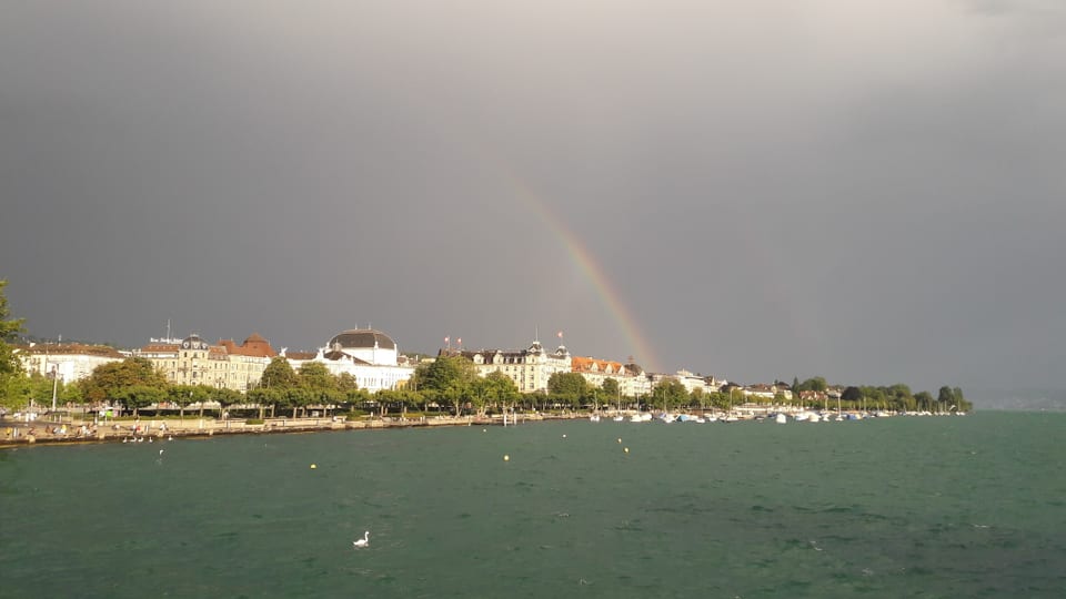 Die vielen Wellen deuten auf einen unruhigen Zürichsee. Der Himmel ist tiefgrau. Einzig der Regenbogen gibt dem Bild etwas Farbe.