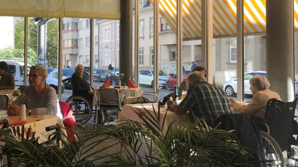 Viele alte Leute sitzen in der Caféteria des Altersheims.