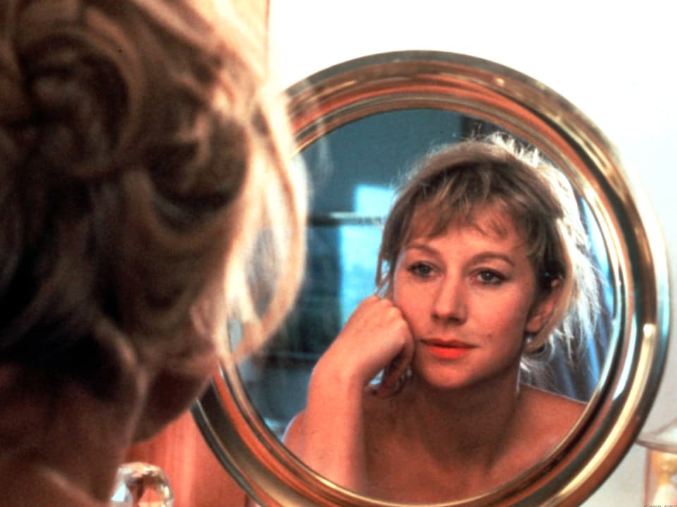Helen Mirren schaut in einen goldenen Spiegel.
