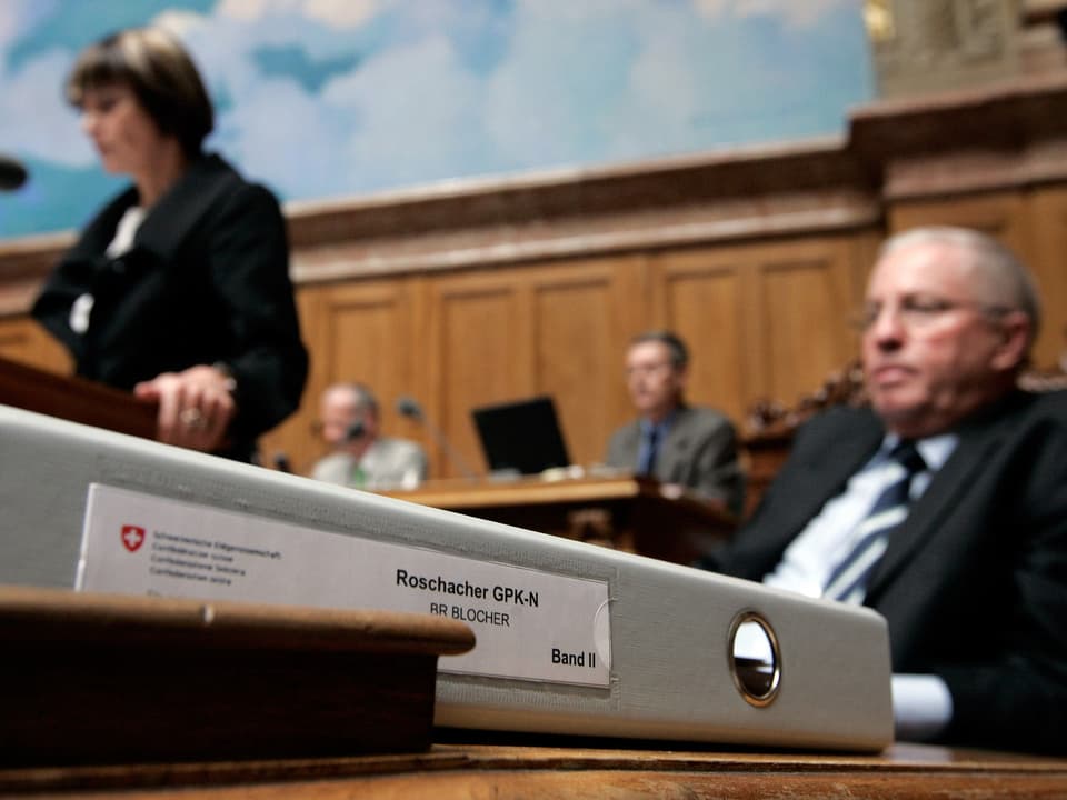 Bundesrat Blocher im Parlament, vor ihm ein Ordner mit der Bezeichnung «Roschacher GPK-N»