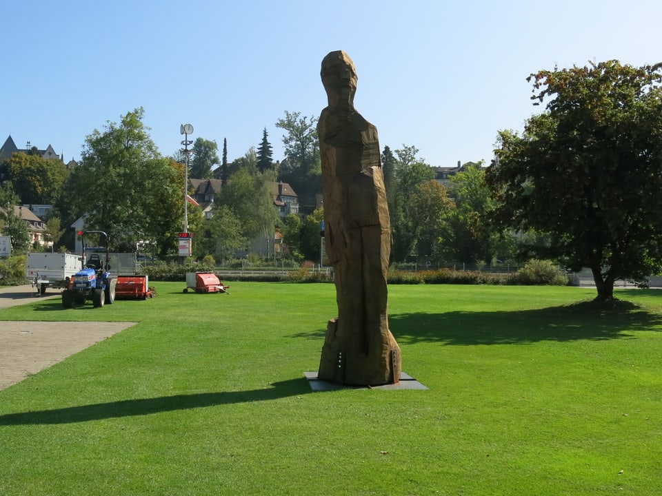 Eine grosse Holzfigur steht auf dem Rasen