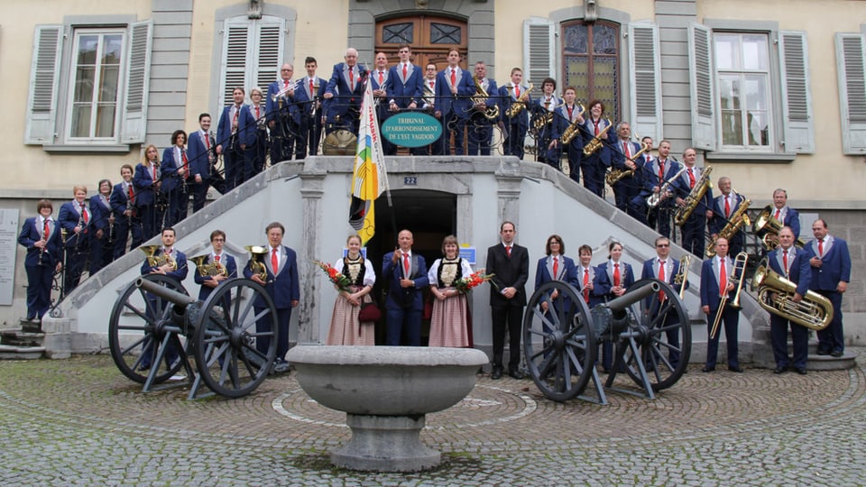 Bild der Stadtmusik Grenchen - Mehrere Musiker stehen auf einer Treppe. Im Vordergrund stehen zwei Kanonen. 