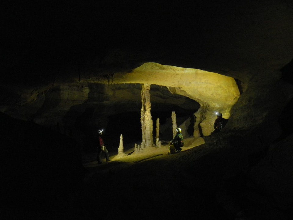 Dunkle Tropfsteinhöhle Malatière mit den typischen Säulen, erhellt durch Taschenlampenlicht.