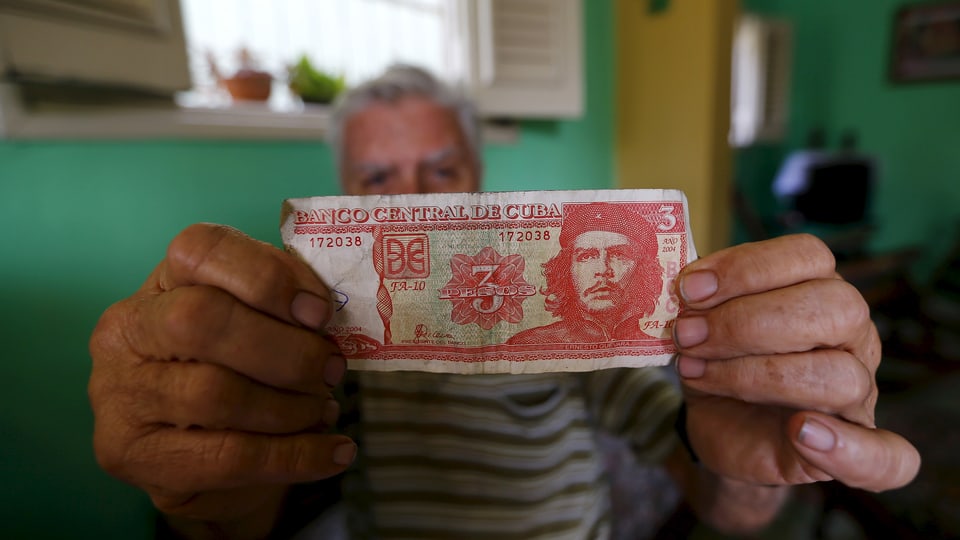 Ein Mann zeigt eine Drei-Peso-Note mit dem Konterfei Che Guevaras.