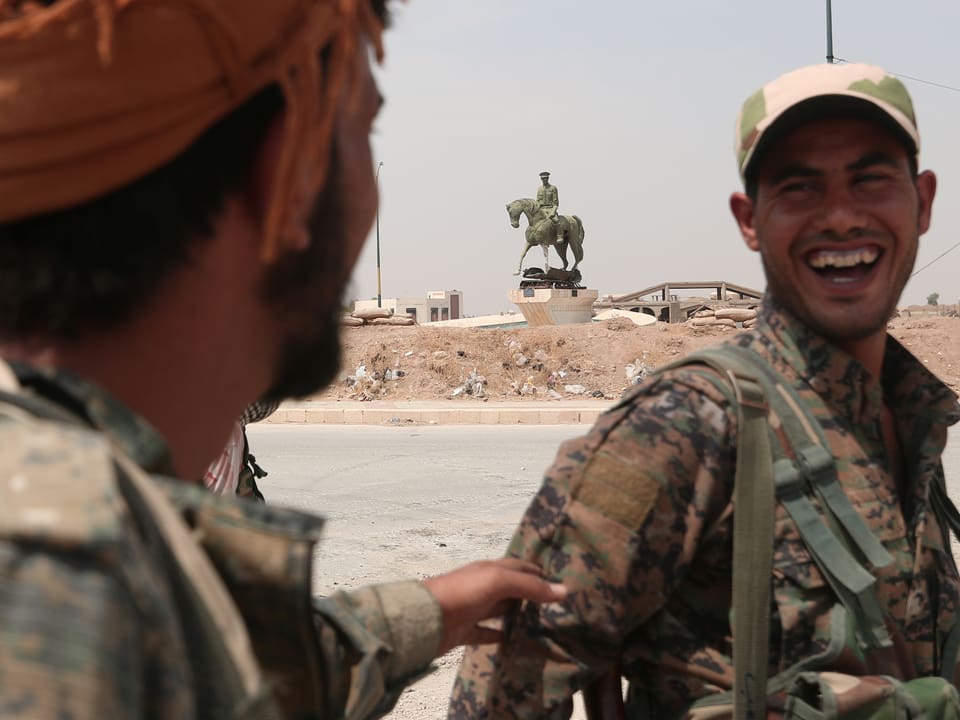 Zwei kurdische Kämpfer lachen sich an