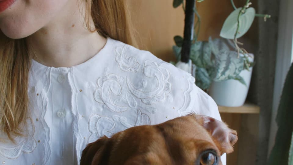 Detailansicht einer jungen Frau mit Hund im Arm.