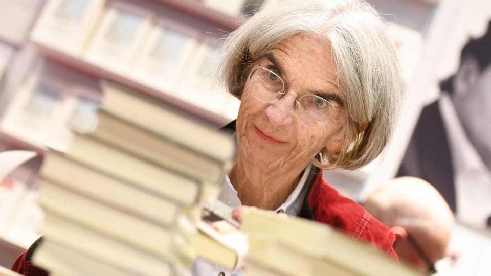 Donna Leon im Porträt vor einem Stapel ihrer Bücher.