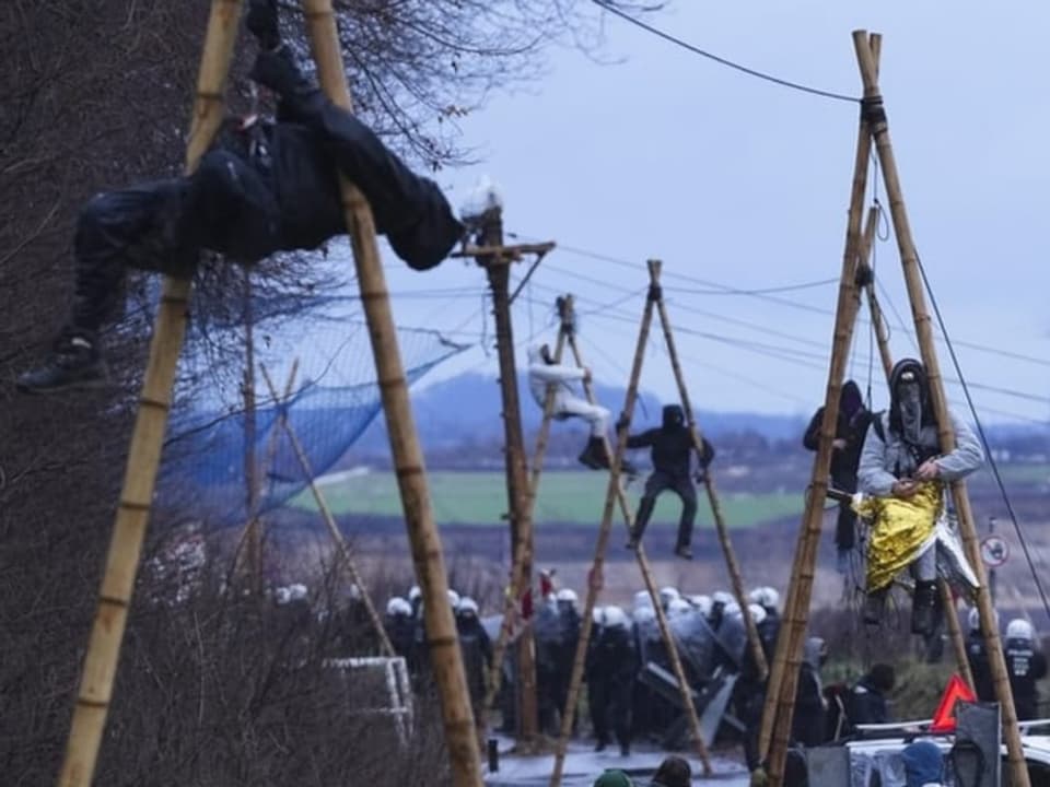 Menschen hängen in Lützerath an Baumstämmen.