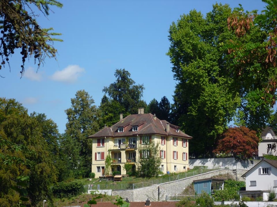 Blick auf das gelbe Haus in Luzern - umrandet von Bäumen