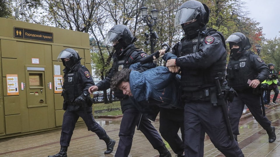 Polizisten in Moskau nehmen einen jungen Mann in Gewahrsam.
