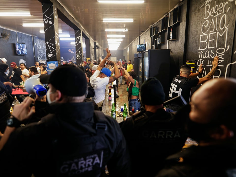 Feiernde und Polizisten in einer Bar