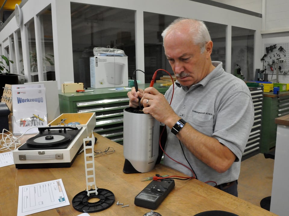 Ein Mann prüft mit zwei Elektroden einen Wasserkocher