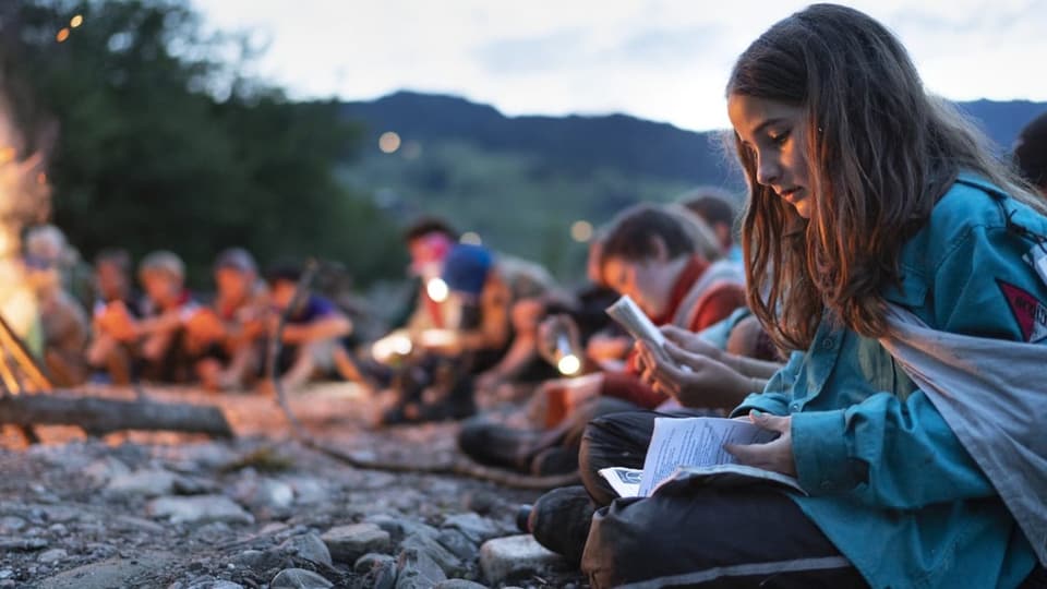 Kinder sitzen in der Dämmerung am Lagerfeuer