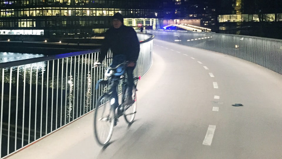 Velofahrer fährt nachts aif einer beleuchteten Velospur.